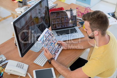 Male executive looking at photos at desk