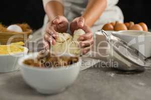 Woman preparing dough surrounded with various ingredients