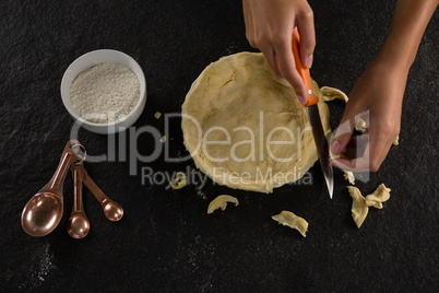 Woman slicing off extra dough from the mold
