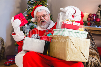 Santa sitting on the sofa with stack of gifts