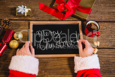 Santa Claus holding a slate with merry christmas text