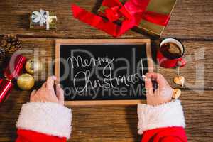 Santa Claus holding a slate with merry christmas text