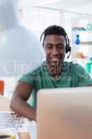 Male executive in headset working over computer at his desk