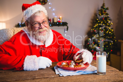 Santa Claus having cookie with a glass of milk