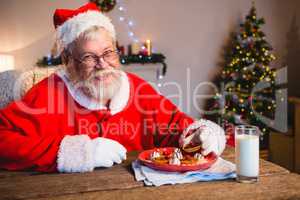 Santa Claus having cookie with a glass of milk