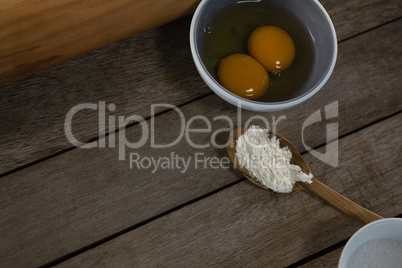 Egg yolk and flour in spoon on a wooden table