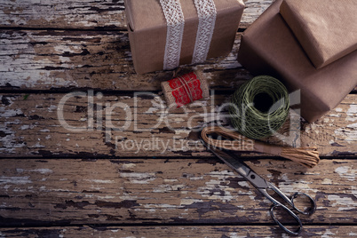 Gift boxes with wrapping material on wooden plank