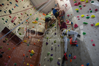 Low angle view of athletes and trainer climbing wall in club