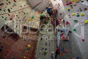 Low angle view of athletes and trainer climbing wall in club