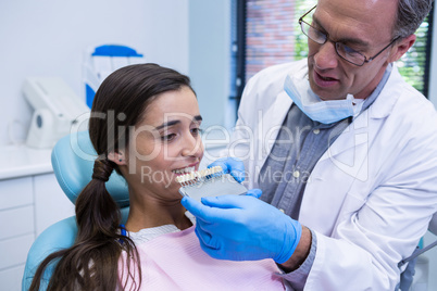 Dentist holding equipment while examining woman