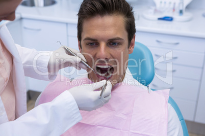 Female doctor giving dental treatment to man at clinic