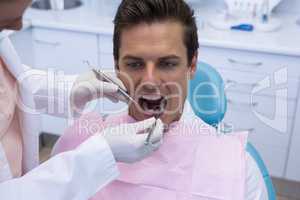 Female doctor giving dental treatment to man at clinic