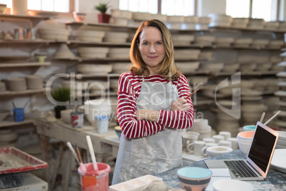 Portrait of female potter standing at worktop