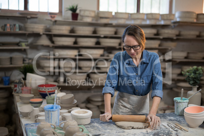 Female potter flattening the clay with rolling pin