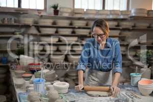 Female potter flattening the clay with rolling pin