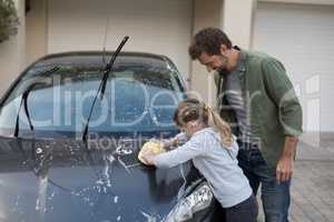 Teenage girl and father washing a car