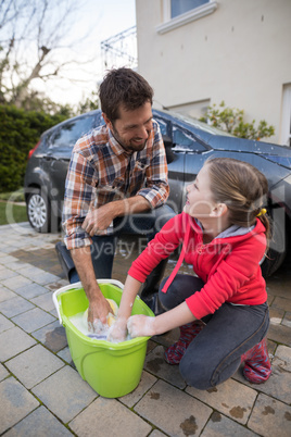 Teenage girl and father washing a car