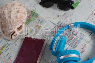 Sunglasses, headphones, passport and seashell on map