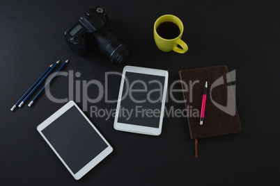 Digital tablet, black coffee, camera, organizer and pen on black background