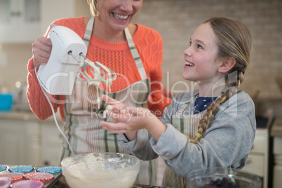 Mother and daughter mixing eggs and wheat flour in a bowl