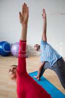 Male Instructor with student practicing triange pose in yoga studio