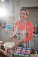 Smiling woman mixing eggs and wheat flour in a bowl