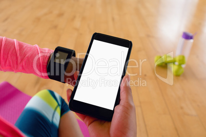 Woman holding mobile hone while using smartwatch