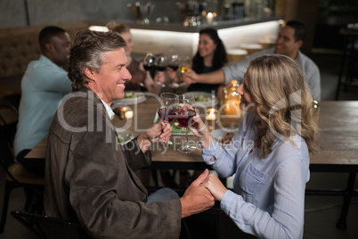 Couple toasting red wine while holding hands