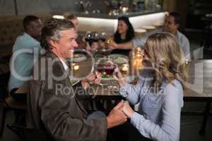 Couple toasting red wine while holding hands