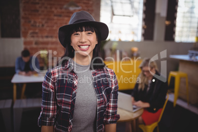 Smiling young woman wearing hat standing at coffee shop