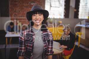 Smiling young woman wearing hat standing at coffee shop
