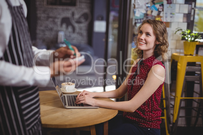Midsection of waiter holding notepad while standing by smiling young female customer Midsection of waiter holding notepad while standing by smiling young female customer