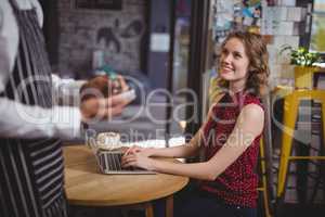 Midsection of waiter holding notepad while standing by smiling young female customer