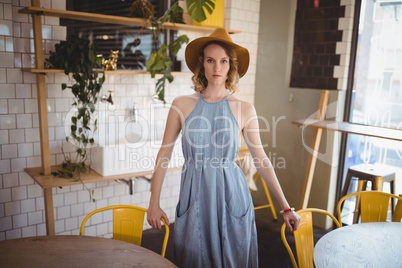 Portrait of confident young woman standing at coffee shop