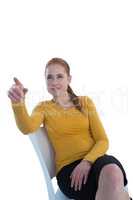 Confident businesswoman pointing while sitting on chair