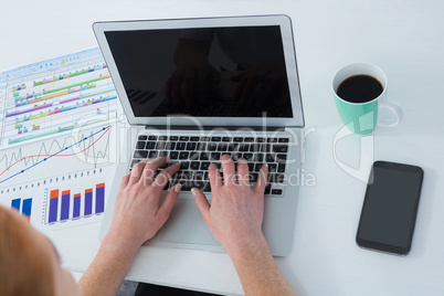 High angle view of businesswoman using laptop by various graphs and data