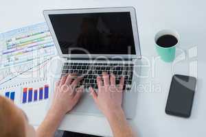 High angle view of businesswoman using laptop by various graphs and data