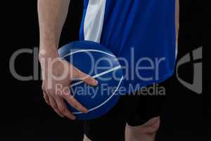 Mid section of player holding basketball