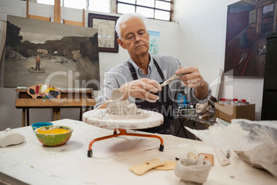 Attentive senior man molding clay