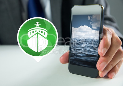 Hand holding phone with ship icon with sea