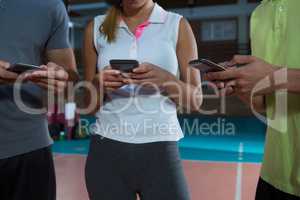 Mid section of players using phones at volleyball court