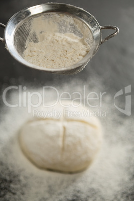 Close up of strainer over bun dough