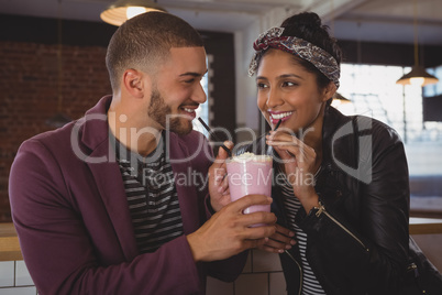 Happy friends enjoying milkshake in cafe