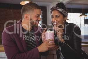 Happy friends enjoying milkshake in cafe