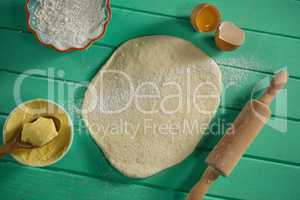 Overhead view of rolled dough by rolling pin and ingredients