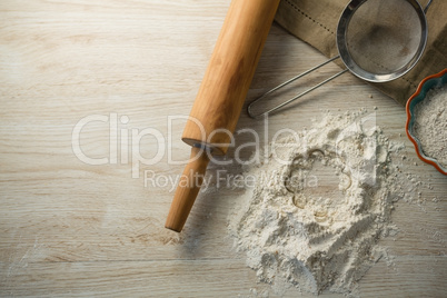Directly above shot of flour in bowl by rolling pin and strainer