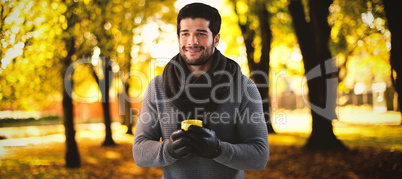 Composite image of smiling man looking away while holding mug of coffee