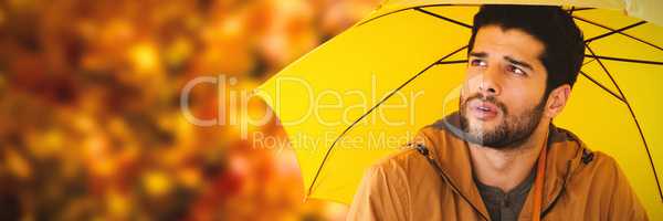 Composite image of thoughtful young man holding yellow umbrella