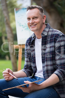 Man holding palette and brush in garden