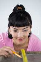 Woman measuring wooden plank with tape measure